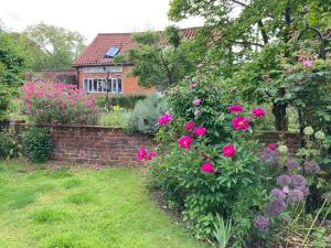 a garden with pink flowers and a brick wall at Simpers Drift, Great Glemham in Saxmundham