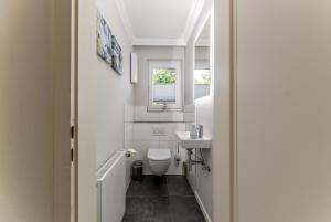a bathroom with a toilet and a sink and a window at Haus Treibholz in Westerland +24 photos