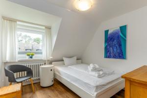 a bedroom with a bed and a chair and a window at Haus Treibholz in Westerland