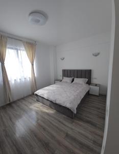 a white bedroom with a large bed and wooden floors at Vera Home 3 in Râmnicu Vâlcea