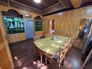 a dining room with a green table and chairs at Aasha's Home in Kalpa