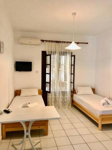 a room with two beds and a table and a tv at Nikos & Panagiota in Vourvourou