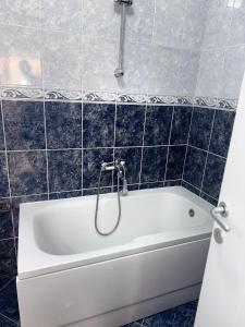 a white bath tub in a bathroom with blue tiles at DarViva Apartment Niš, center, private garage parking, river view in Niš +22 photos