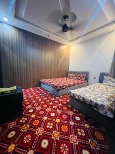 two beds in a room with a red carpet at AL AQSA SUiTES Guest House Islamabad in Islamabad