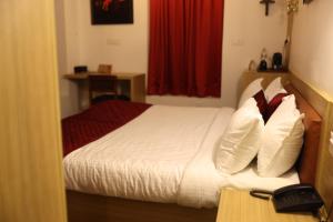 a bedroom with a bed with white sheets and pillows at Chithrapuri Heritage Hotels Pvt Ltd in Alattūr