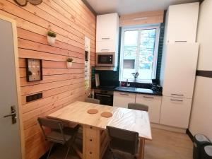 a kitchen with a wooden wall with a table and chairs at Petit cocon centre MONT DORE in Le Mont-Dore