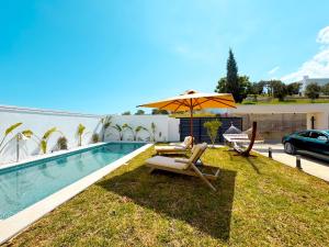 a swimming pool with two lounge chairs and an umbrella at villa Alba: luxe et confort a Hammamet in Hammamet Nord