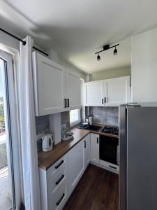 a kitchen with white cabinets and a refrigerator at Apartament Chełmiec przy Szczawnie-Zdrój in Wałbrzych
