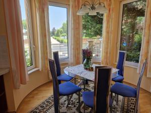 a dining room with a table and chairs and windows at Sunshine Beach House, DIREKT AM SEE, eigenes BOOT, PRIVATE BEACH, Grill, WLAN in Szántód