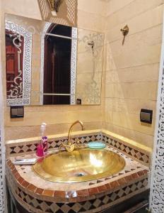 a bathroom with a gold sink and a mirror at maison d'hôtes Le petit jardin Marrakech in Marrakech