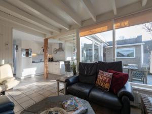 un salon avec un canapé en cuir et une cuisine dans l'établissement Bungalow in Sint Maartenszee near Beach, à Sint Maartensvlotbrug 96 autres photos