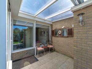 - une véranda avec 2 chaises et une table sur la terrasse dans l'établissement Bungalow in Sint Maartenszee near Beach, à Sint Maartensvlotbrug