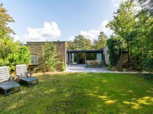 a brick house with two chairs in a yard at Bungalow in Sint Maartenszee near the beach in Sint Maartensvlotbrug