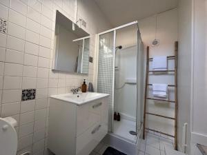 Un baño blanco con lavabo y ducha. en Cozy appartement 2 chambres au coeur de Palaiseau 8min RER B à pieds, en Palaiseau 9 fotos más