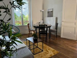 Una sala de estar con una mesa y sillas y una ventana. en Cozy appartement 2 chambres au coeur de Palaiseau 8min RER B à pieds, en Palaiseau