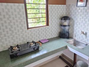 a kitchen counter with a stove and a sink at Greenwood Cabins Maroon House in Jorhat +4 photos
