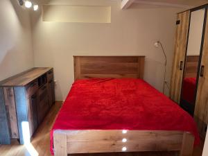 a bedroom with a wooden bed with a red bedspread at Haus Anke in Selce
