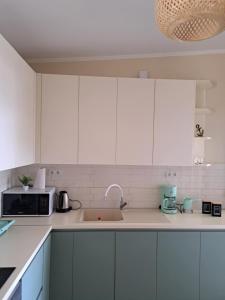 a kitchen with white cabinets and a sink and a microwave at Dream house Peramos in Nea Peramos