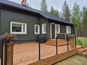 a green house with a deck and a house at Villa Kaikuranta in Nellimö