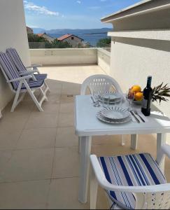 a white table with a plate of fruit and a bottle of wine at Apartment Lana Maris studio 2 - 200m from beach, terrace with sea view, wi-fi and free parking in Dramalj