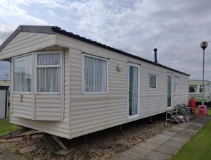 a white house with windows on a yard at Happy Days Seaside Trusthorpe in Trusthorpe