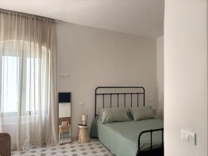 a white bedroom with a bed and a window at B&B Casa Uliva in Castellaneta