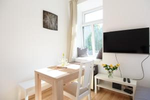 biała jadalnia ze stołem i telewizorem w obiekcie Vienna City Apartment Kempelengasse w Wiedniu