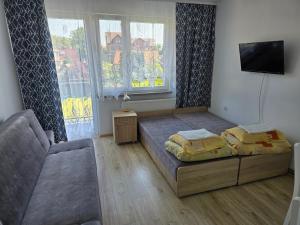 a bedroom with a bed and a couch and a tv at Pokoje Gościnne Elżbieta Chylińska in Krynica Morska