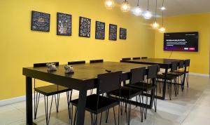 una sala da pranzo con tavoli e sedie neri e una parete gialla di BTS Asoke 6bedroom townhouse a Bang Kapi