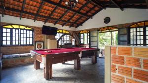 a pool table in a room with a brick wall at Chácara bello Rio in Guaratuba
