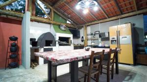 a kitchen with a table with chairs and a refrigerator at Chácara bello Rio in Guaratuba