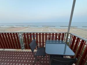 a table and chairs on a balcony with the beach at SN VistaMare in Lido di Classe