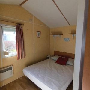 een kleine slaapkamer met een wit bed en een raam bij Camping Baroudeurs in Lagraulière