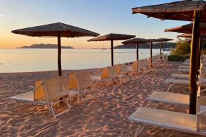 a row of chairs and umbrellas on a beach at Hotel Don Diego in Porto San Paolo