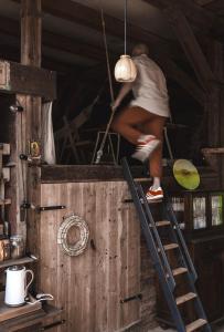 a man climbing a ladder in a wooden cabin at Wietorówka in Lubomierz