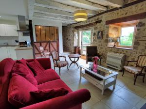ein Wohnzimmer mit einem roten Sofa und einem Tisch in der Unterkunft Maison en pierre avec piscine in Billac