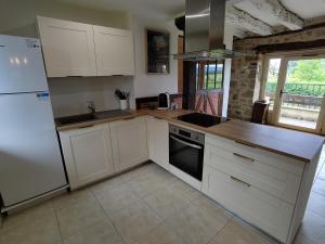 eine Küche mit weißen Schränken und einem weißen Kühlschrank in der Unterkunft Maison en pierre avec piscine in Billac + 20 Fotos