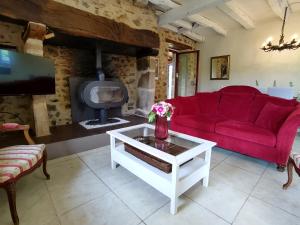 ein Wohnzimmer mit einem roten Sofa und einem Kamin in der Unterkunft Maison en pierre avec piscine in Billac