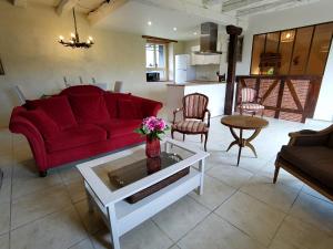 ein Wohnzimmer mit einem roten Sofa und einem Tisch in der Unterkunft Maison en pierre avec piscine in Billac