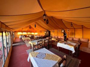 a person standing in a tent with tables and chairs at Najma Desert Camp in Merzouga