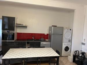 a kitchen with a table and a stove and a refrigerator at Le Paquebot - Near Les Chantiers de l'Atlantique in Saint-Nazaire