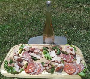 un tagliere con carne e una bottiglia di vino di Maison pétanque piscine 2 à 6 personnes a Chevigny-en-Valière