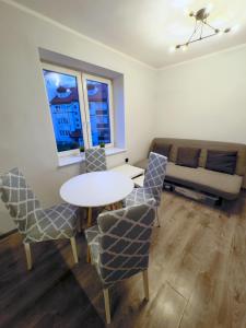 Una sala de estar con una mesa y sillas y un sofá. en MorzePort Władysławowo, en Władysławowo