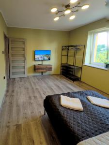 Un dormitorio con una cama y un televisor en la pared. en MorzePort Władysławowo, en Władysławowo