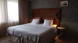 a bedroom with a bed with white sheets and a window at Home Hotel Fregatten in Varberg +31 photos