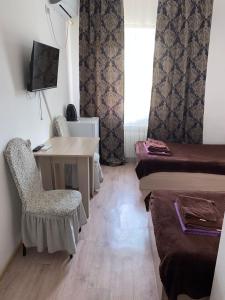 Piccola camera con scrivania, letto e tavolo. di Гостиница ОАЗИС a Atyraū