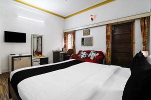 a hotel room with a white bed and a red chair at Hotel O Salt lake City in Kolkata