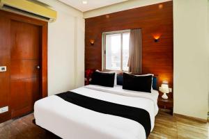 a bedroom with a large white bed with a window at Hotel O Airport Road in Ahmedabad