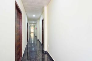a hallway of a building with white walls and black tile floors at Hotel O Malkajgiri Mandal in Hyderabad