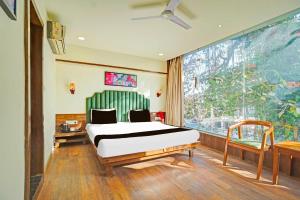 a bedroom with a bed and a large window at Hotel O Arvind Marg Pachamarhi in Pachmarhī